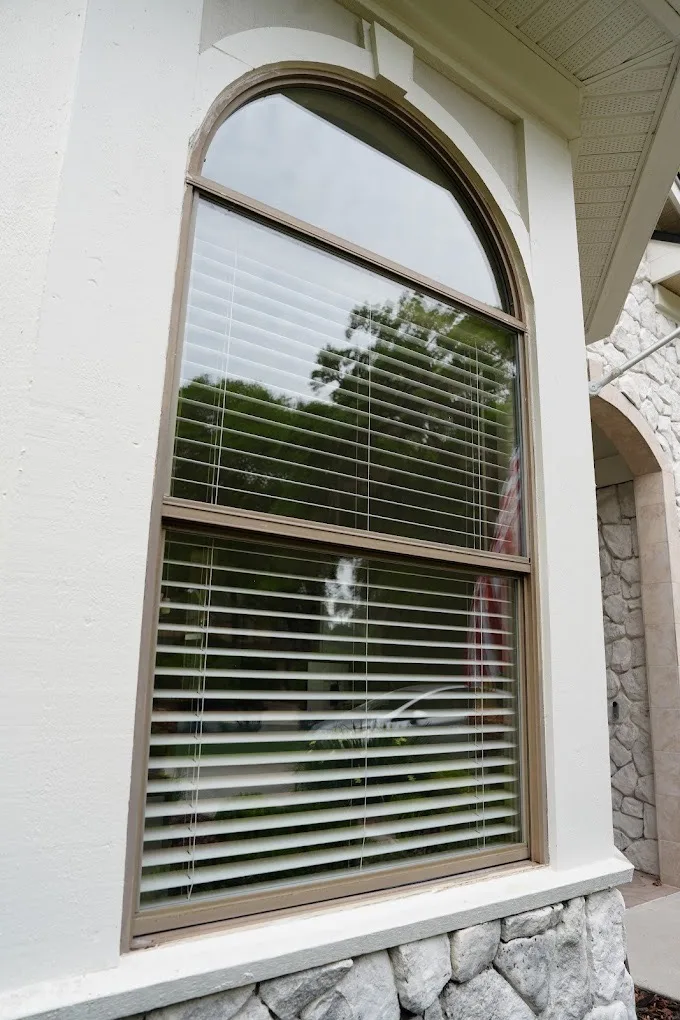 Restored arched window on a stone-front home after hard water stain removal